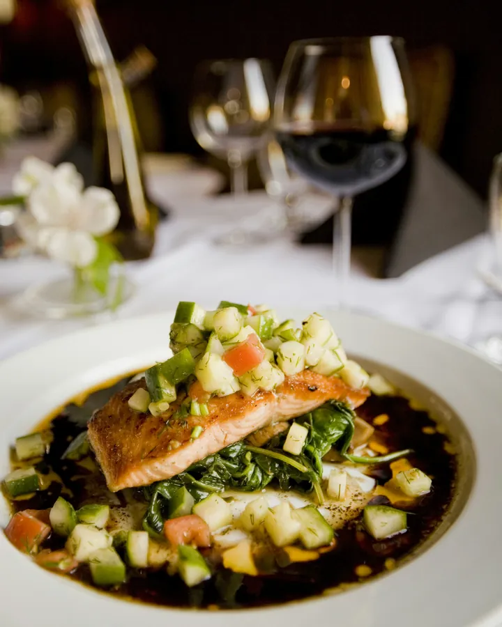 A fillet of salmon with a fine cucumber and tomato salsa, on white linen.
